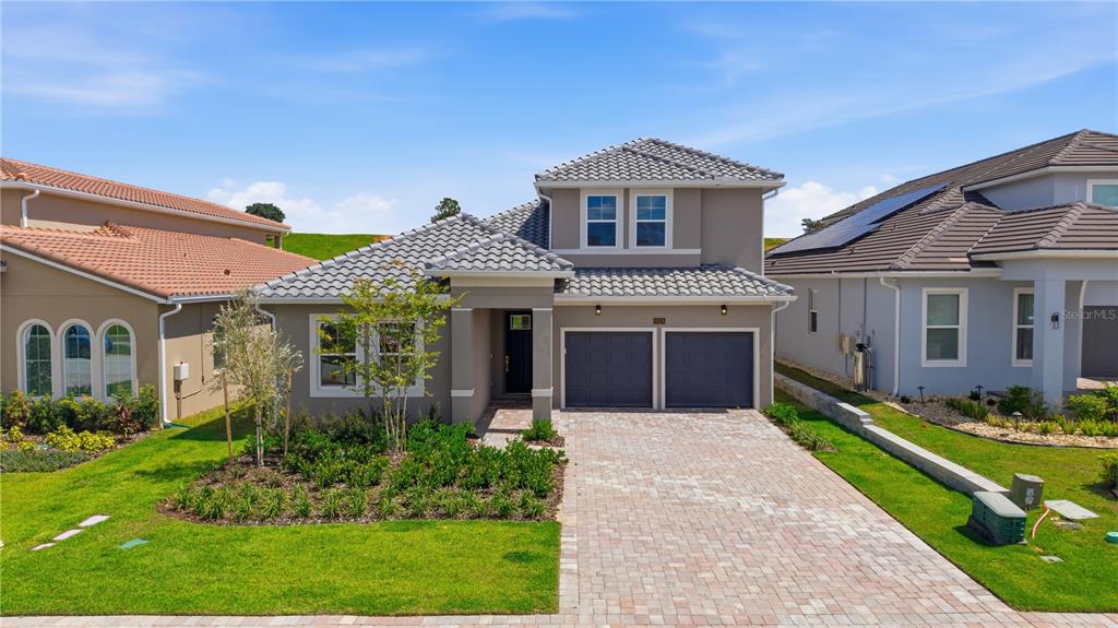A two-story suburban house with a gray tile roof, stucco exterior, and a paved driveway — 16114 VOLTERRA POINT, BELLA COLLINA, FL