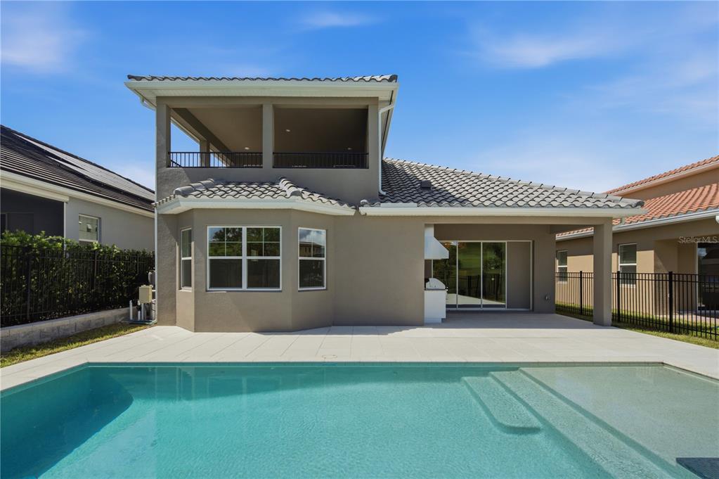 The exterior of a two-story house features a swimming pool and a covered patio area — 16114 VOLTERRA POINT, BELLA COLLINA, FL