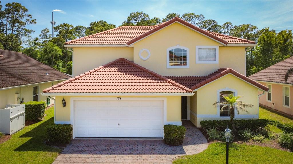 A two-story yellow house with a red tile roof and a two-car garage — 135 ROBIN ROAD, DAVENPORT, FL