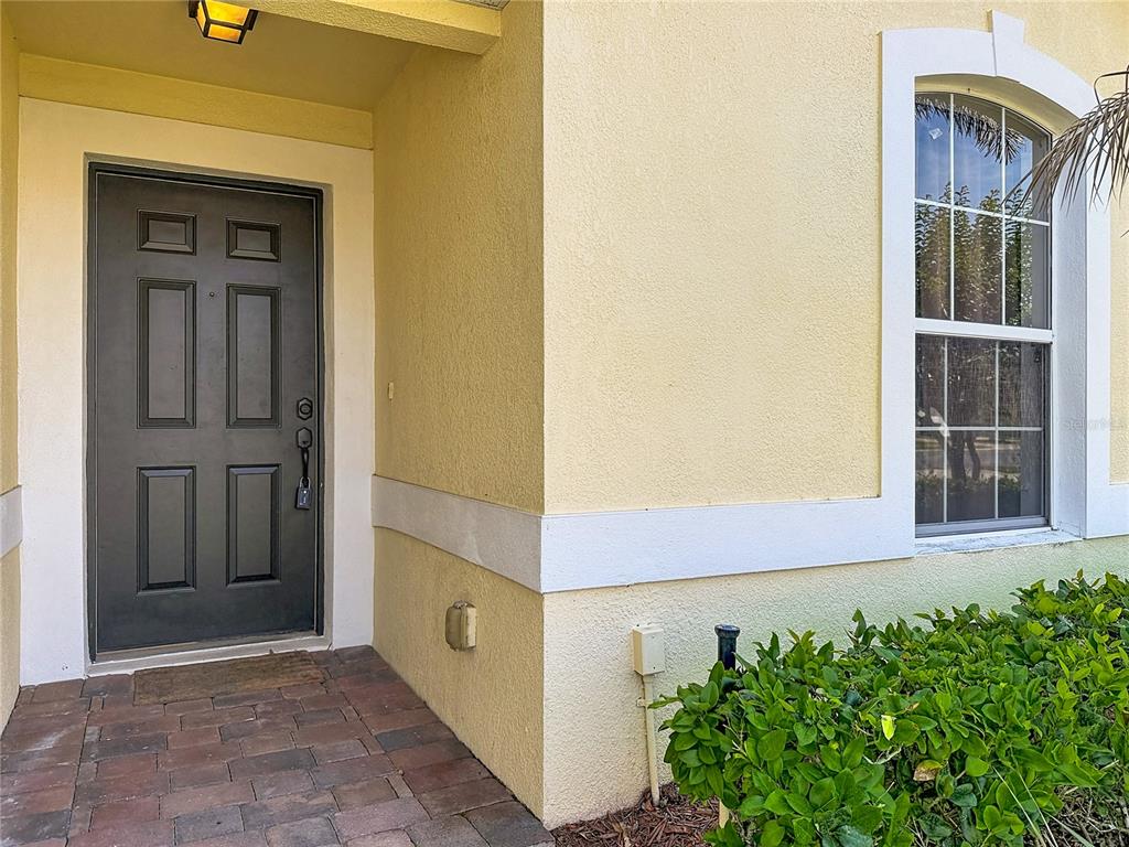 A dark front door with a rectangular window sits beside a window on a stucco house — 135 ROBIN ROAD, DAVENPORT, FL