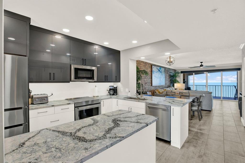 A living room features a brick accent wall, a large sectional sofa, and a balcony — 16450 GULF BOULEVARD UNIT 763, NORTH REDINGTON BEACH, FL