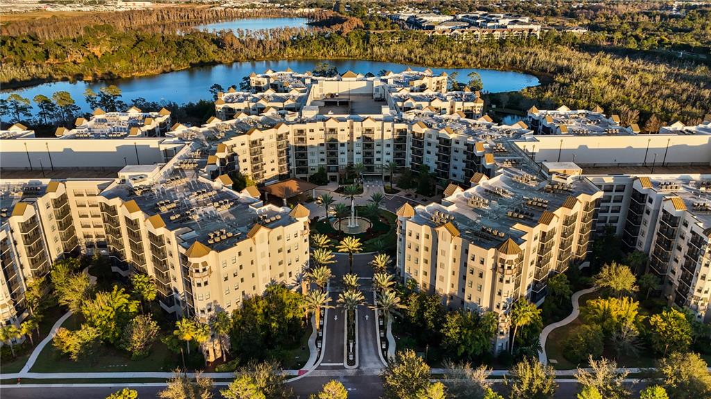 An aerial view of a large multi-story apartment complex with a central courtyard and lake — 14501 GROVE RESORT AVENUE UNIT 2542, WINTER GARDEN, FL