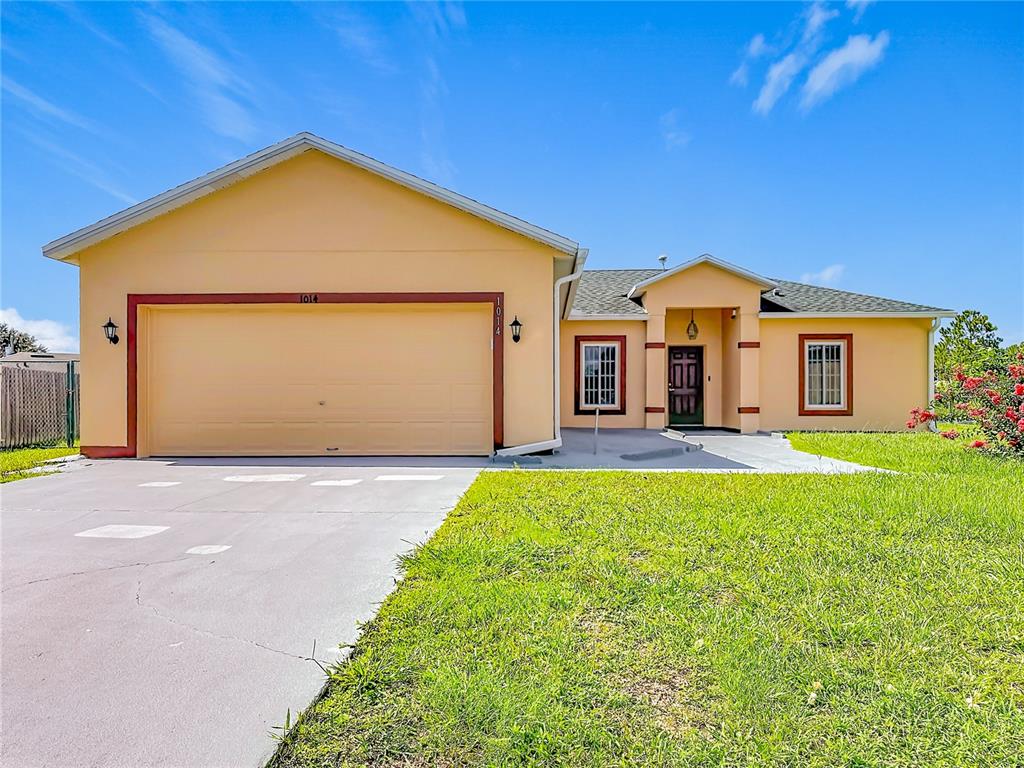 A single-story house with a yellow stucco exterior, a two-car garage, and a front entrance — 1014 DEDDINGTON PLACE, KISSIMMEE, FL