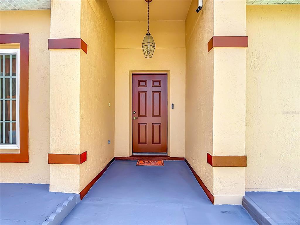 A front entryway features a red door, a hanging lantern, and a blue concrete porch — 1014 DEDDINGTON PLACE, KISSIMMEE, FL