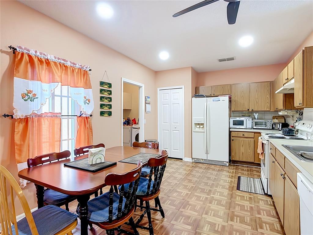 A kitchen and dining area with wood cabinets, light-colored walls, and patterned vinyl flooring — 1014 DEDDINGTON PLACE, KISSIMMEE, FL