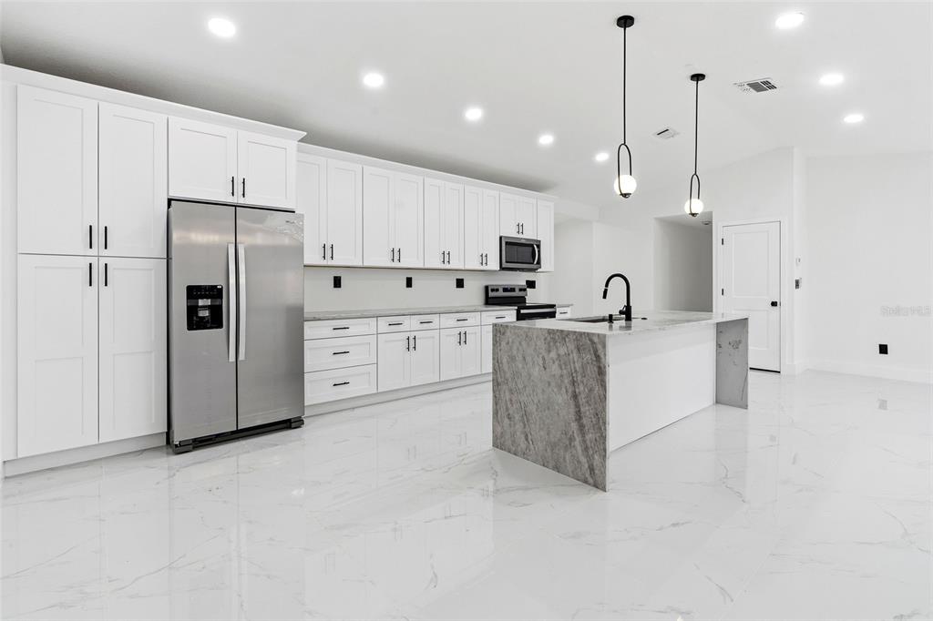 A single-story house with white stucco walls, a black garage door, and a dark roof — 5308 BLACK PINE DRIVE, TAMPA, FL
