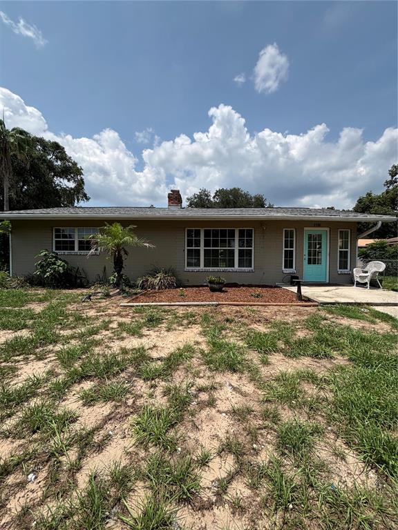 A single-story house with a light-colored exterior, a turquoise front door, and a grassy yard — 13381 SE 106TH COURT, OCKLAWAHA, FL