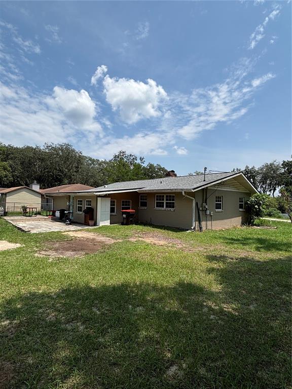 The exterior of a single-story tan house with a shingled roof and a patio — 13381 SE 106TH COURT, OCKLAWAHA, FL