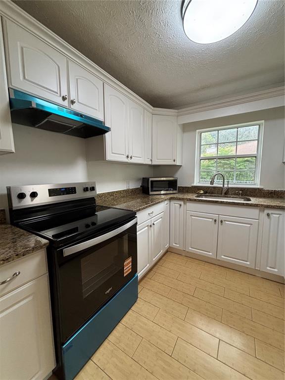 A kitchen features white cabinets, granite countertops, a black stove, and light-colored tile flooring — 13381 SE 106TH COURT, OCKLAWAHA, FL