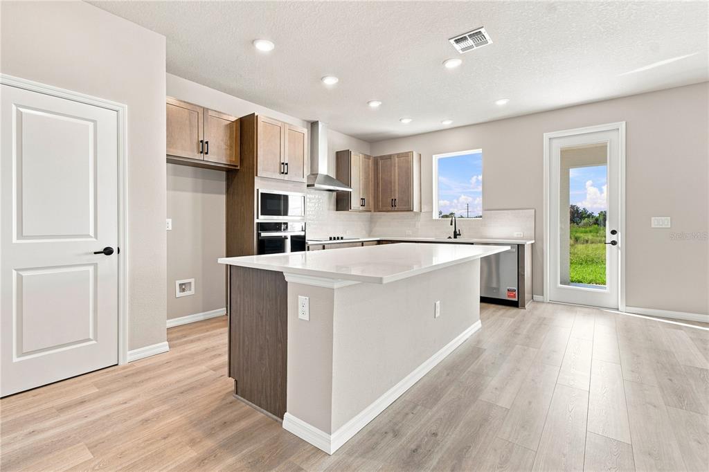 The rear exterior of a two-story house features a covered patio and a sandy yard — 3417 YELLOW CASSIA DRIVE, WESLEY CHAPEL, FL