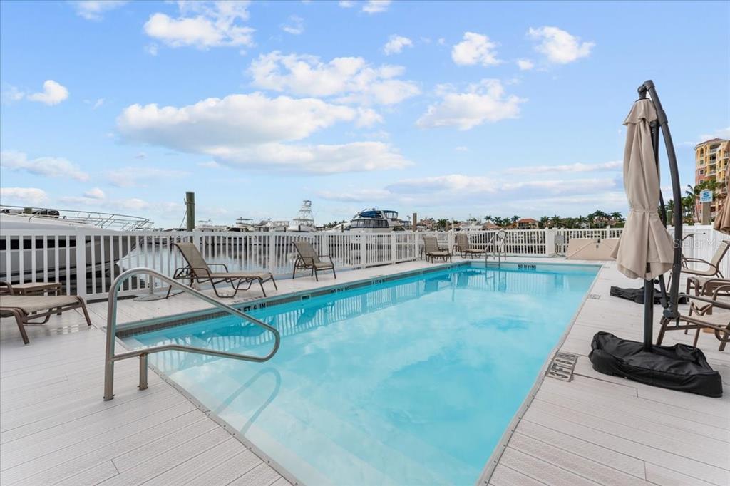 An outdoor swimming pool on a deck overlooks a marina with docked boats — 102 RIVIERA DUNES WAY UNIT S-7, PALMETTO, FL