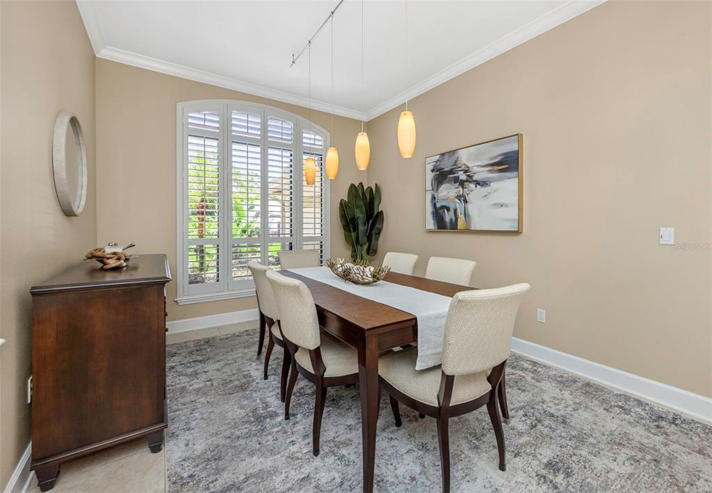 An entryway with tile floors leads to a dining area featuring a chandelier and windows — 3675 JANUS WAY, PALM HARBOR, FL