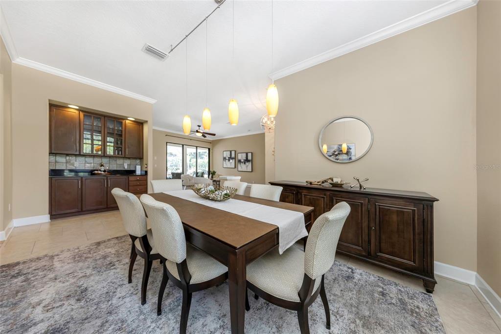 A dining room features a wooden table, six upholstered chairs, pendant lights, and arched shutters — 3675 JANUS WAY, PALM HARBOR, FL