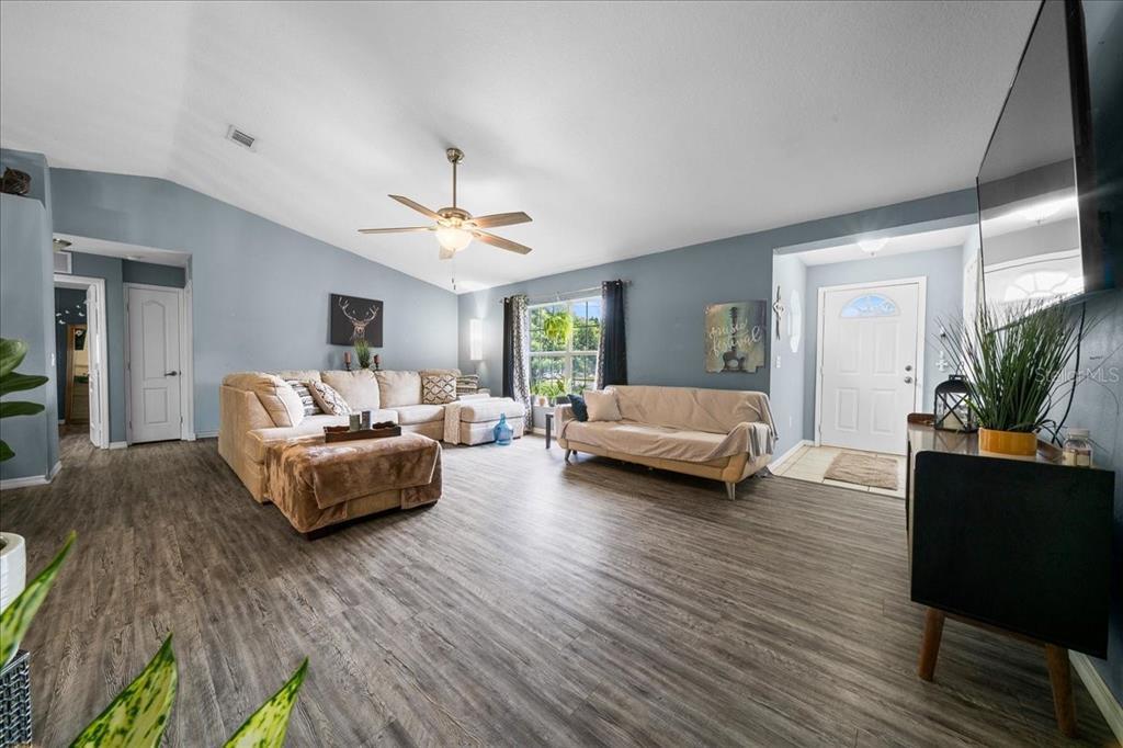 A living room features light blue walls, wood-look flooring, a ceiling fan, and two sofas — 9 PINE CIRCLE RUN, OCALA, FL
