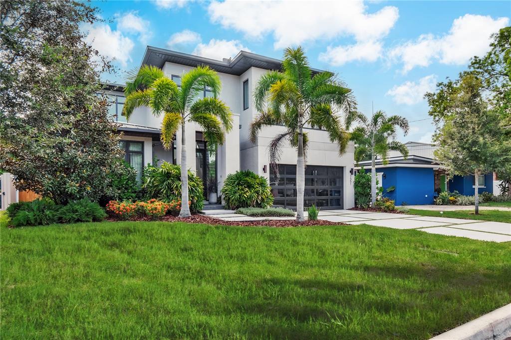 A modern two-story house with a gray garage, palm trees, and a green front lawn — 1551 PASADENA DRIVE, DUNEDIN, FL