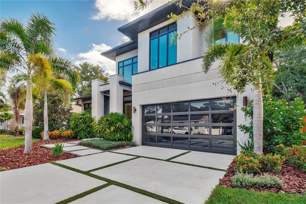 A modern two-story house features a glass-paneled garage door and a concrete paver driveway — 1551 PASADENA DRIVE, DUNEDIN, FL