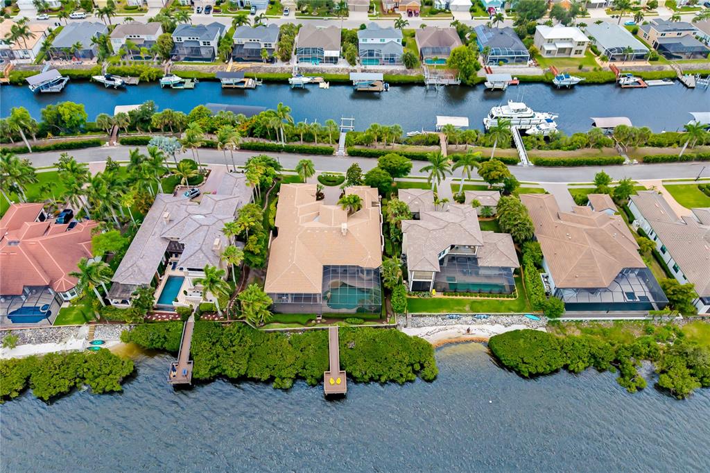 An aerial view shows waterfront homes with private boat docks along a canal at sunset — 3803 HAWK ISLAND DRIVE, BRADENTON, FL