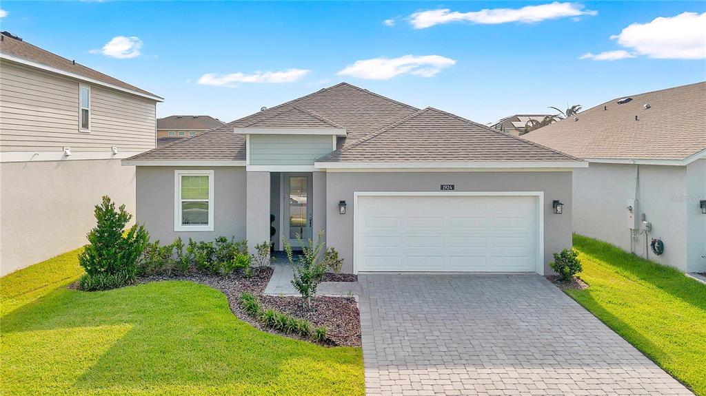 A single-story house with a gray stucco exterior, a two-car garage, and a paved driveway — 1924 COLUMBUS PATH, ST CLOUD, FL