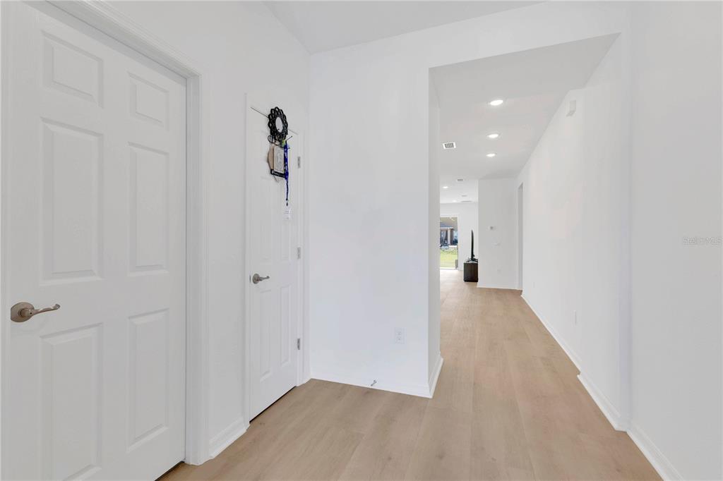 A bright entryway with light wood flooring leads to a hallway and an open living area — 1924 COLUMBUS PATH, ST CLOUD, FL