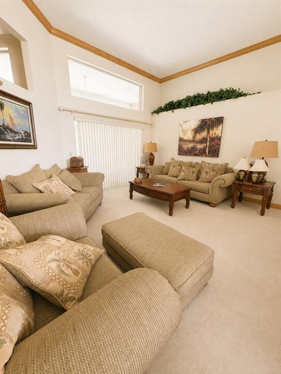 A living room features beige furniture, a wooden coffee table, and high ceilings with windows — 995 WEATHERSFIELD DRIVE, DUNEDIN, FL