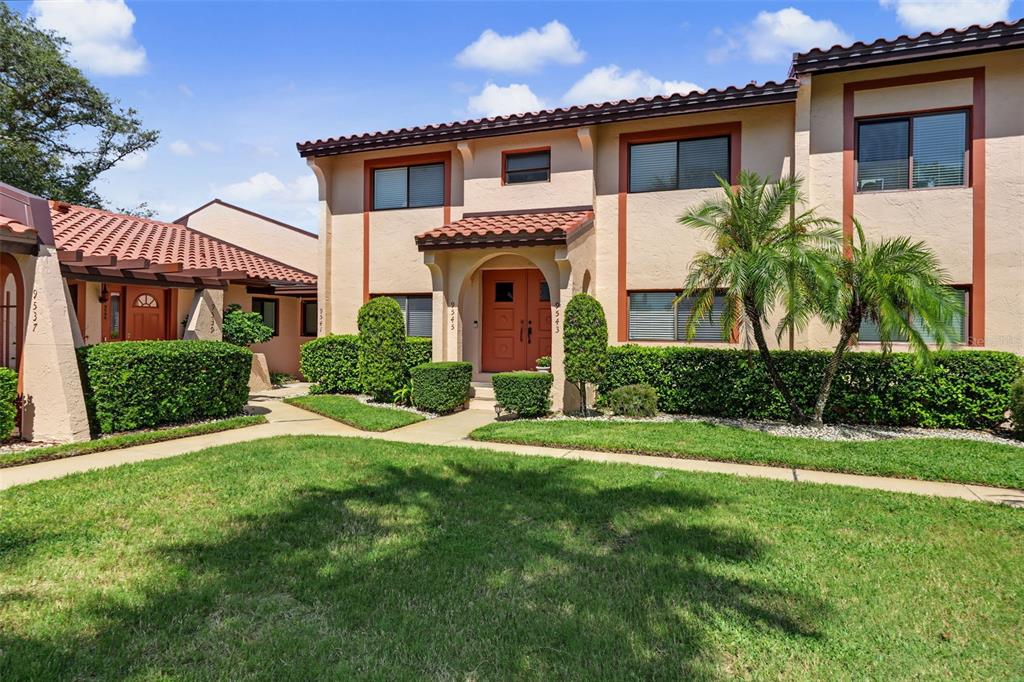 A two-story stucco apartment building features a red tile roof and a central entryway — 9543 86TH AVENUE UNIT 9543, SEMINOLE, FL