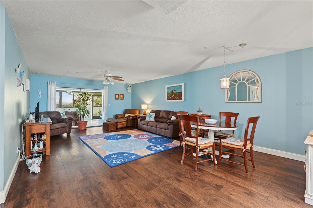 A living and dining area with blue walls, wood flooring, and a patterned area rug — 9543 86TH AVENUE UNIT 9543, SEMINOLE, FL