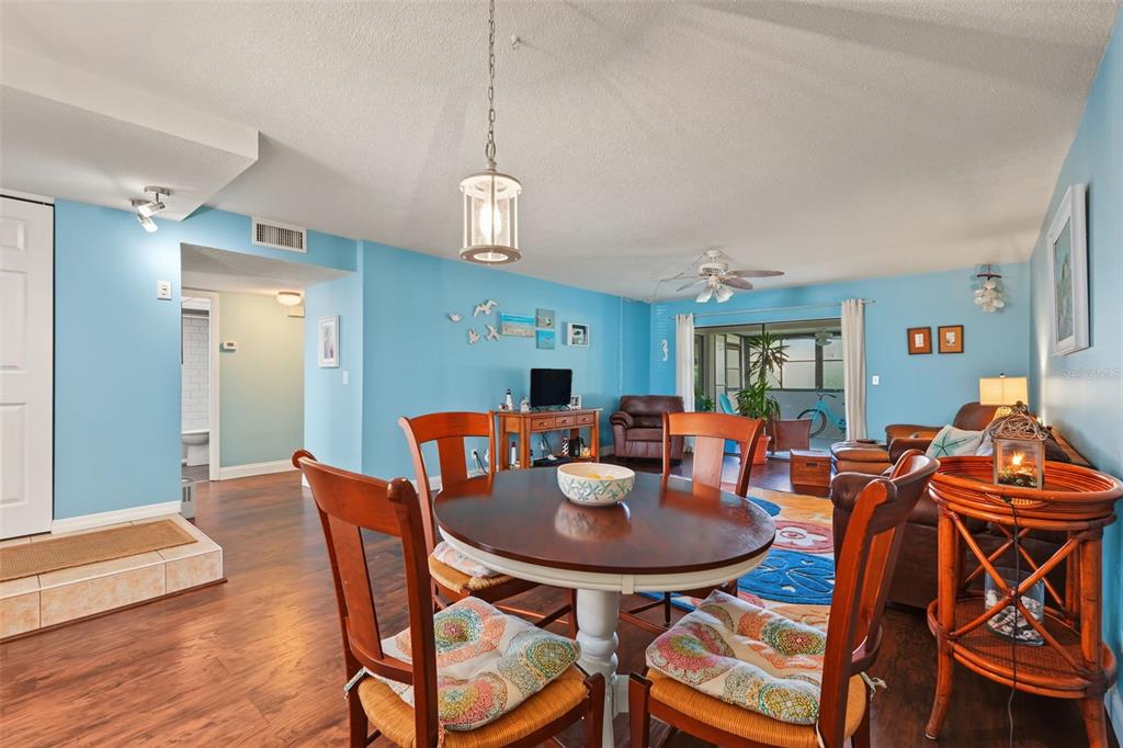 A dining area with a round wooden table and chairs opens into a blue-walled living room — 9543 86TH AVENUE UNIT 9543, SEMINOLE, FL
