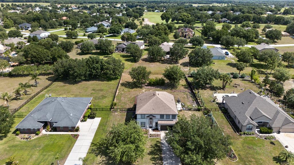 An aerial view shows three suburban houses with large yards surrounded by trees and greenery — 24215 WELDON DRIVE, EUSTIS, FL