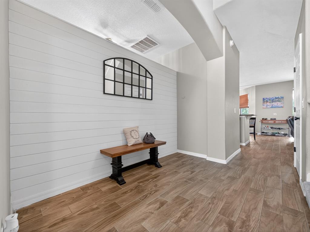 An entryway features a shiplap accent wall, a wooden bench, and wood-look tile flooring — 24215 WELDON DRIVE, EUSTIS, FL