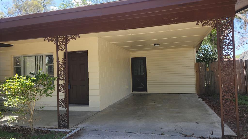 A house exterior features a concrete carport, two dark doors, and decorative metal support columns — 908 WESTMORE AVENUE, BRANDON, FL