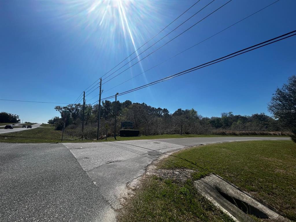 A sunny, outdoor view of a road intersection with a small sign and trees — US HWY 301, BELLEVIEW, FL