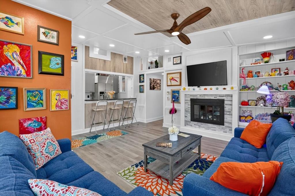 A living room features blue sofas, a fireplace, a kitchen pass-through, and colorful wall art — 1520 60TH STREET S, GULFPORT, FL