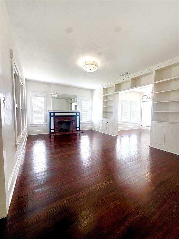A living room features dark hardwood floors, a brick fireplace, and white walls — 1903 CURRY FORD ROAD, ORLANDO, FL