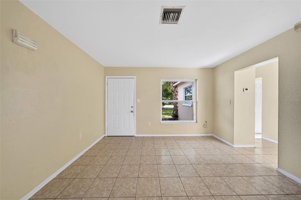 A room with beige walls, tile flooring, a white front door, and a single window — 2985 SAINT CHARLES STREET, FORT MYERS, FL