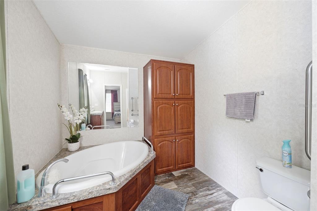 A bathroom features a corner soaking tub, a tall wooden cabinet, and a toilet — 3183 CEDLEY ROAD, DADE CITY, FL