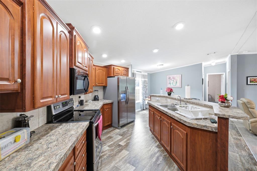 A kitchen with wood cabinets, stainless steel appliances, and a central island with a sink — 3183 CEDLEY ROAD, DADE CITY, FL