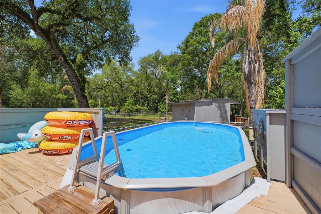 An oval above-ground swimming pool sits on a wooden deck in a backyard — 3183 CEDLEY ROAD, DADE CITY, FL