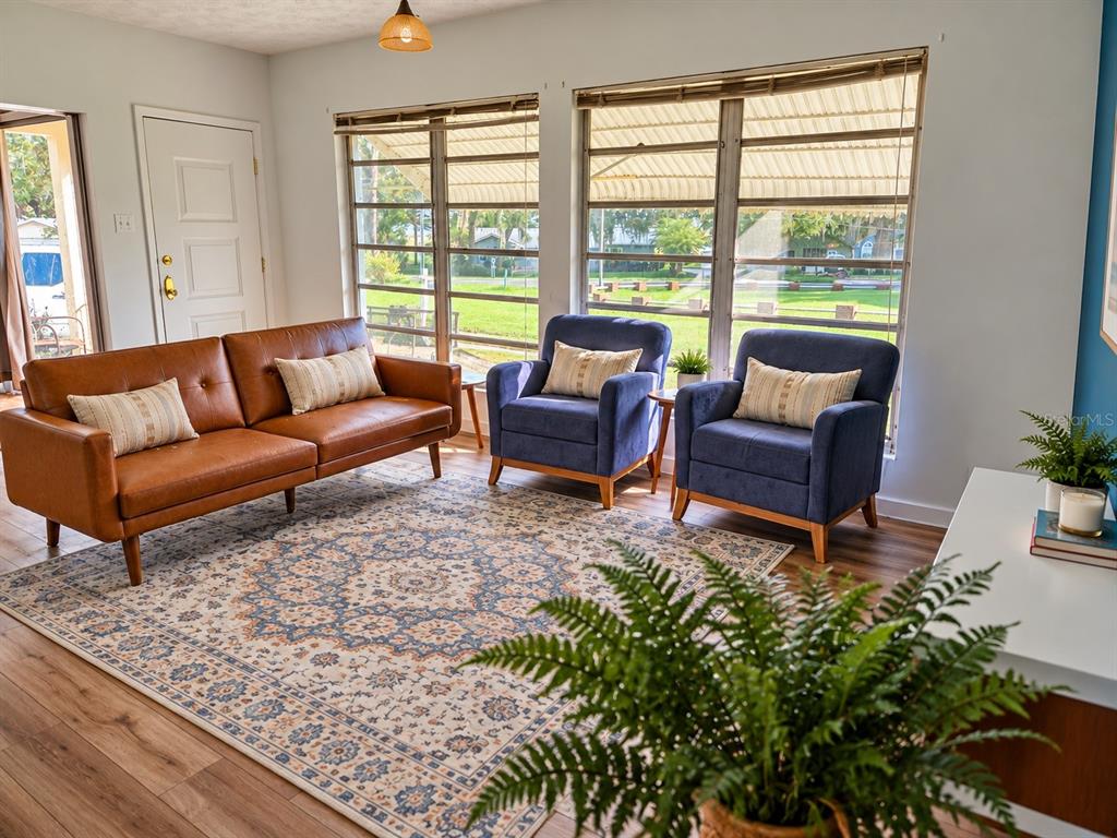 A kitchen with white cabinets, stainless steel appliances, and a wood-topped island opens to a room — 665 SE HERON STREET, KEYSTONE HEIGHTS, FL