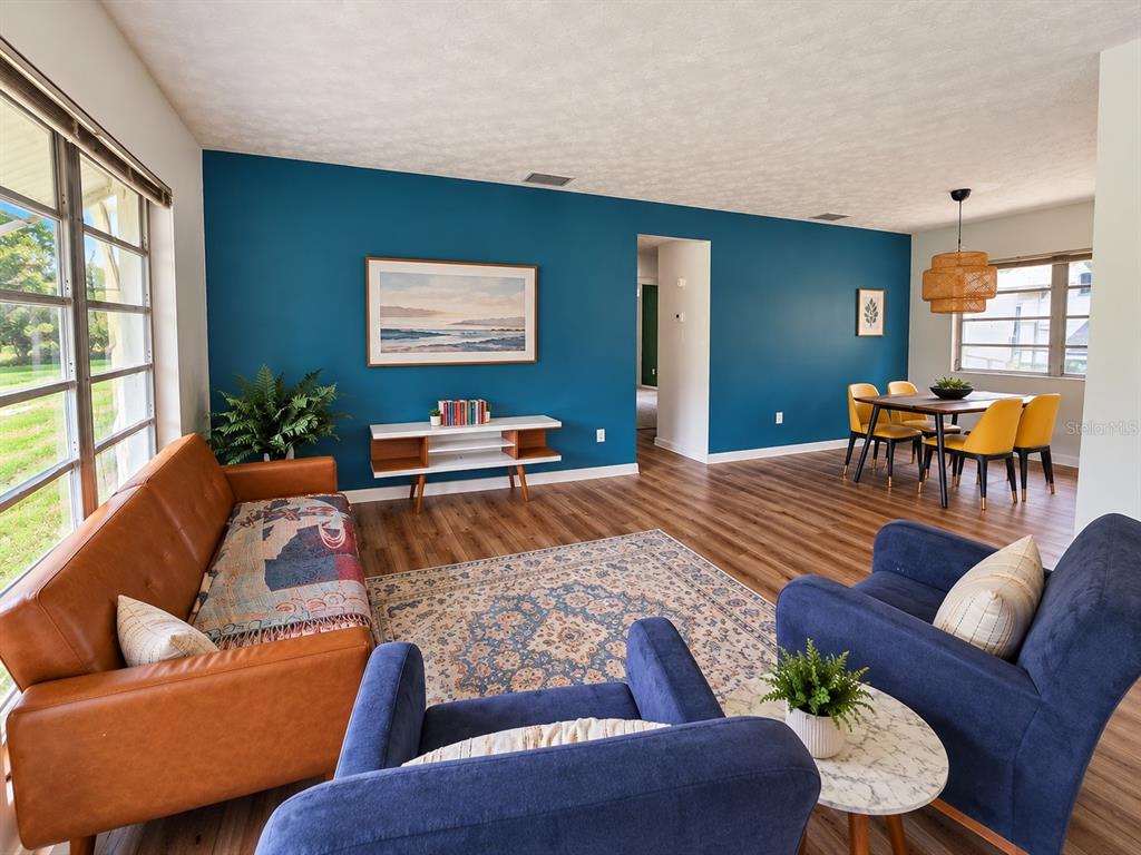 A kitchen features white cabinets, stainless steel appliances, a rolling island, and wood-look flooring — 665 SE HERON STREET, KEYSTONE HEIGHTS, FL