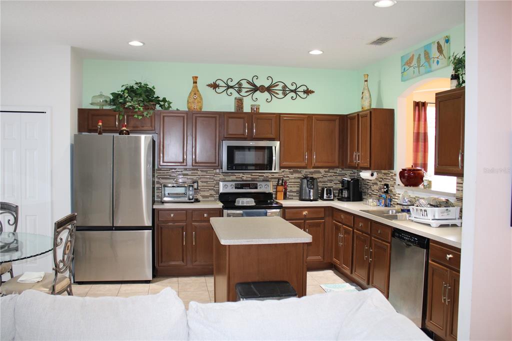 A kitchen with dark wood cabinets, stainless steel appliances, a center island, and light-green walls — 463 PALOMA DRIVE, DAVENPORT, FL