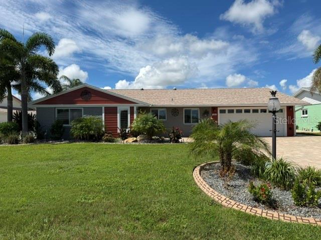 A single-story house with a paved driveway, a two-car garage, and palm trees in front — 1804 BUNKER HILL DRIVE, SUN CITY CENTER, FL