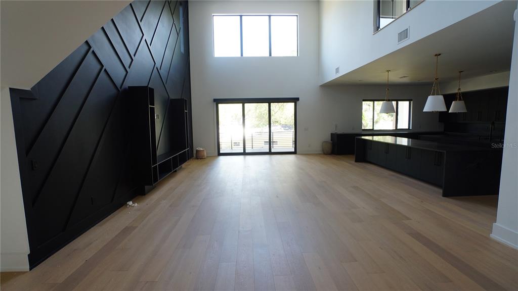 A spacious living area features light wood floors, a black accent wall, and a modern kitchen — 4717 W ESTRELLA STREET, TAMPA, FL