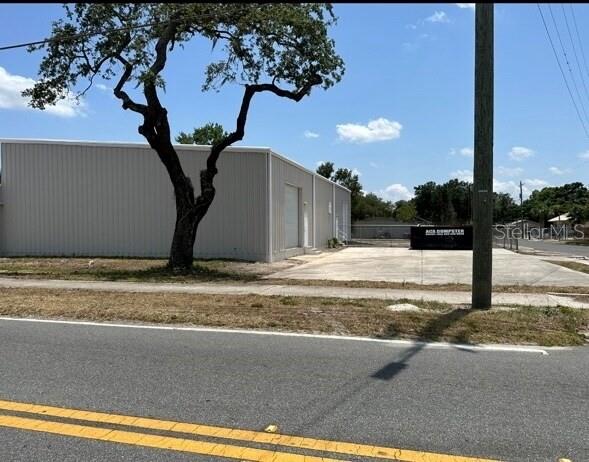 A metal-sided commercial building stands next to a large tree and a paved parking lot — 1604 OLIVE STREET, LAKELAND, FL