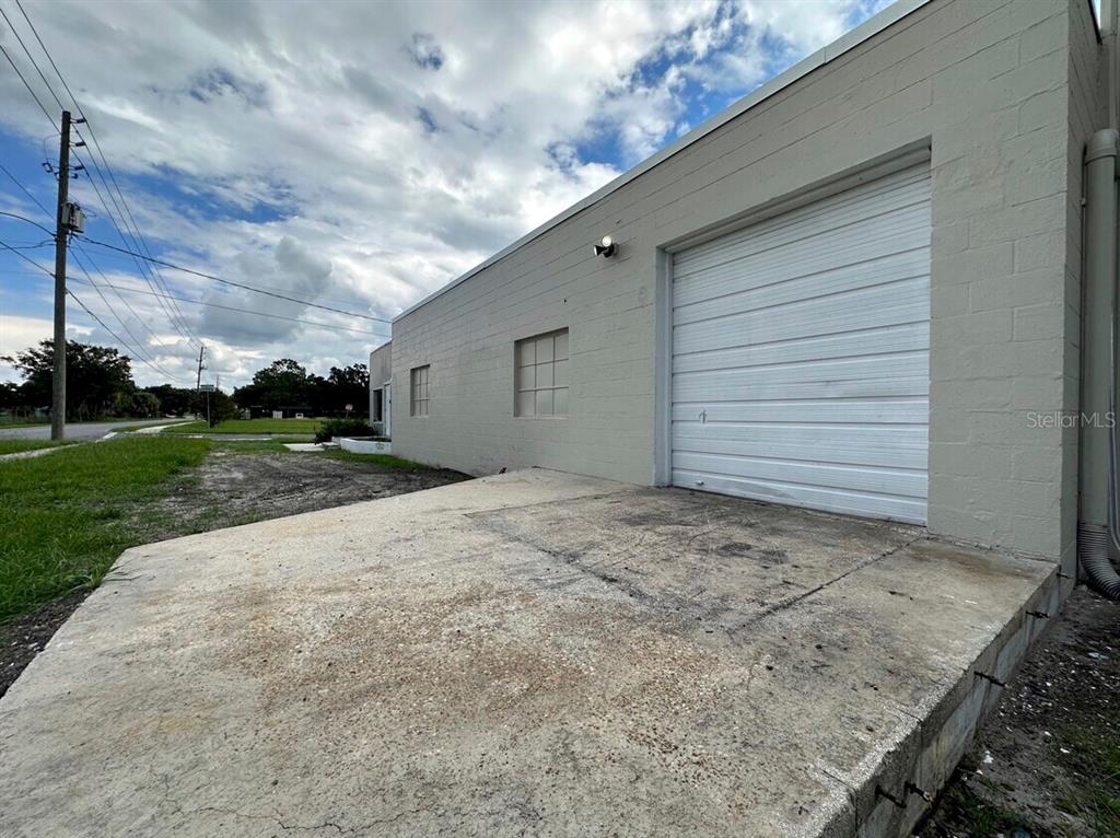 An exterior view of a beige concrete block building with a white roll-up garage door — 1604 OLIVE STREET, LAKELAND, FL