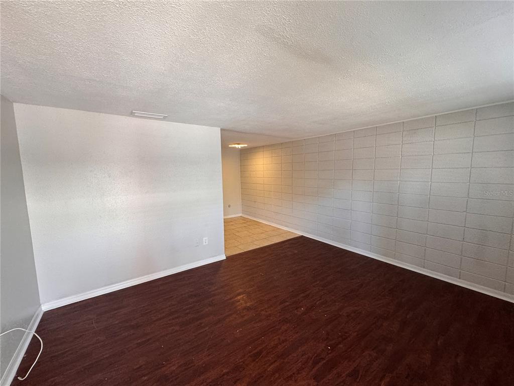 An interior room features dark wood-look flooring, a white wall, and a gray block wall — 121 E PATTERSON STREET UNIT 123, LAKELAND, FL