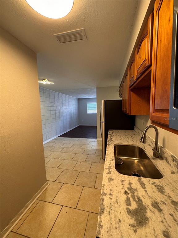 A kitchen with granite countertops and wood cabinets overlooks a living area with tiled floors — 121 E PATTERSON STREET UNIT 123, LAKELAND, FL
