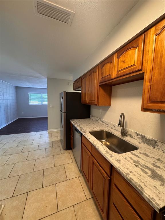 A kitchen features wooden cabinets, a stainless steel sink, and a black refrigerator — 121 E PATTERSON STREET UNIT 123, LAKELAND, FL