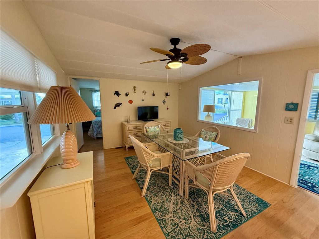 A dining area features a glass-topped table, wicker chairs, a ceiling fan, and light wood flooring — 6091 PEONY ROAD, VENICE, FL