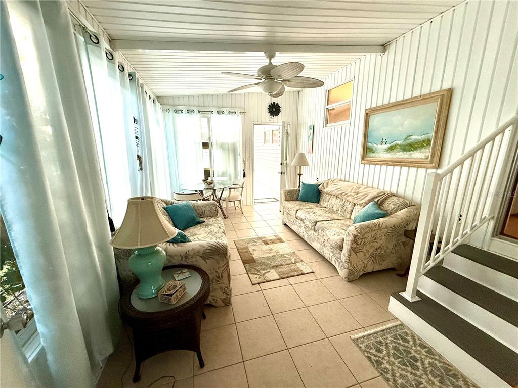 A sunroom features tile flooring, a ceiling fan, two sofas, and a staircase — 6091 PEONY ROAD, VENICE, FL