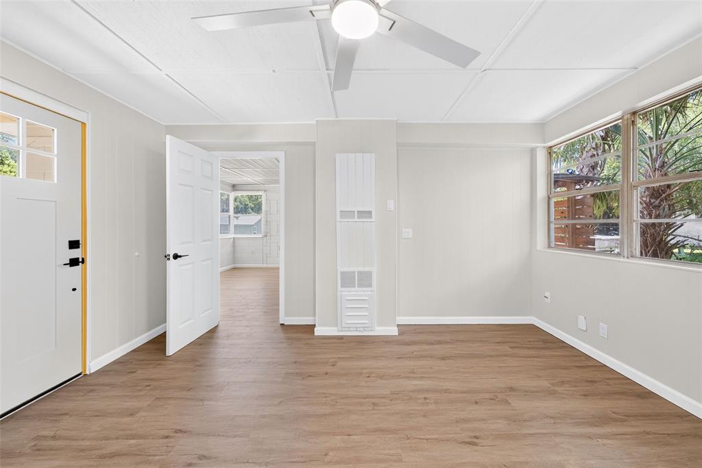 A bright room features light-colored walls, wood-look flooring, a ceiling fan, and a wall heater — 1202 E CAROLINE STREET, TAVARES, FL